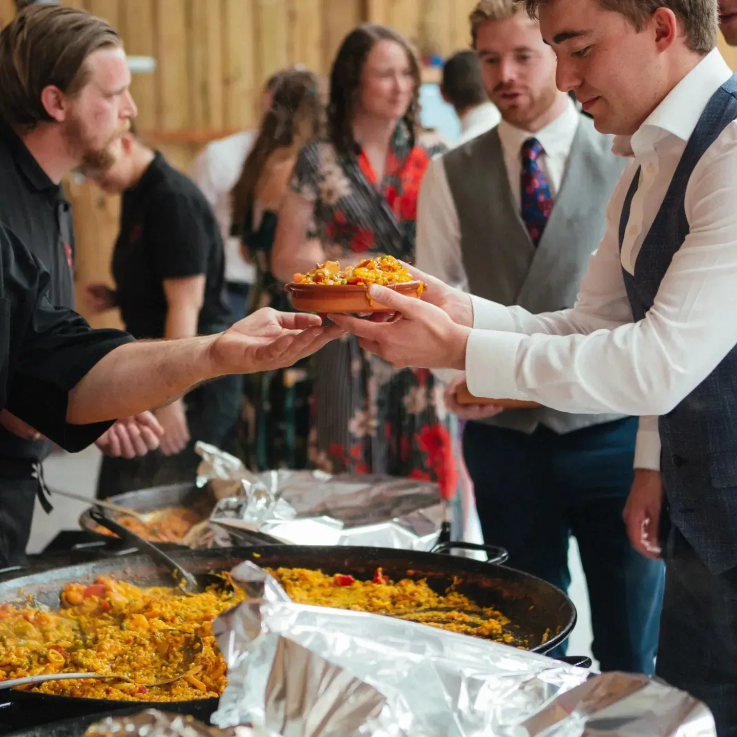 A Buen Apetito team member serving paella to wedding guests, during a wedding reception
